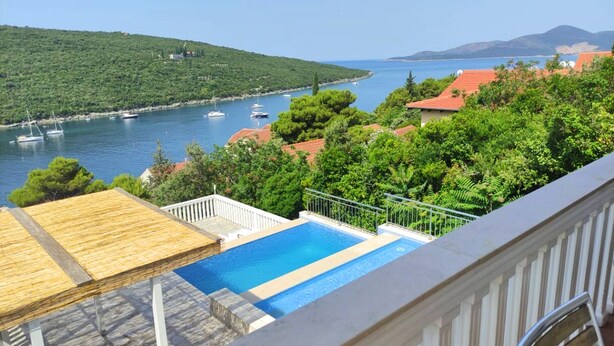 A pool with a view of a bay with boats, surrounded by greenery and buildings with red roofs. - SPACIOUS VILLA - OWN PRIVATE POOL, WIFI,  STUNNING SEA VIEWS (Bigova)