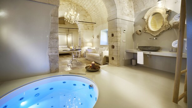 A luxurious bathroom with a large bathtub, a chandelier, and a stone archway. - Wonderful Charming Villa with pool in the suggestive countryside near the sea, (RAGUSA)