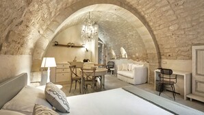 A bedroom with an arched stone ceiling, a bed with patterned pillows, a desk with a chair, and a hanging chandelier. - Wonderful Charming Villa with pool in the suggestive countryside near the sea, (RAGUSA)