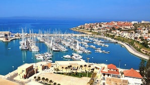 A marina with numerous boats docked, a curved breakwater, and a coastal town in the background. - Wonderful Charming Villa with pool in the suggestive countryside near the sea, (RAGUSA)