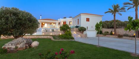 A modern house with a well-maintained lawn, large rocks, and flowering plants.