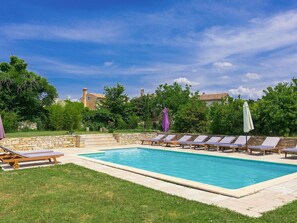 Relax by the serene pool surrounded by lush greenery and a stone wall.