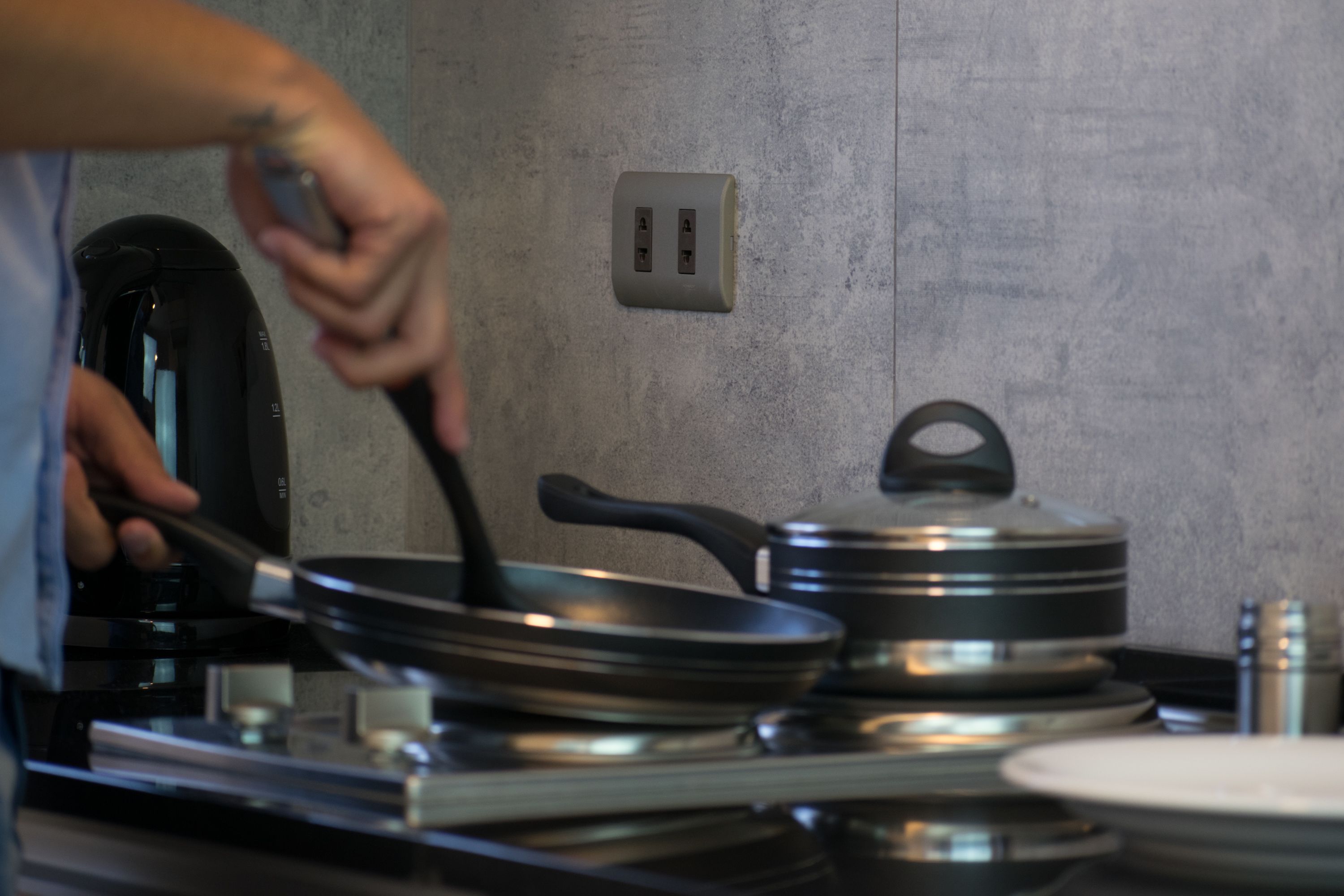 A kitchen with a stove, pots, and a hand stirring a pan.
