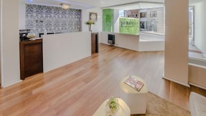 A modern reception area with a wooden floor, a reception desk, and a green accent wall. - Fratelli Aparthotel (La Paz)