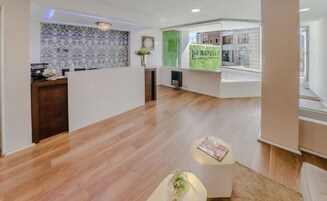 Un área de recepción moderna con suelo de madera, mostrador de recepción y pared verde de acento.
