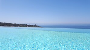 Ein klares, blaues Schwimmbecken mit Blick auf eine Küstenlandschaft und eine entfernte Insel.