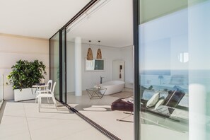 Ein modernes Wohnzimmer mit großem Fenster, einer Couch, einem Couchtisch und einer Zimmerpflanze.