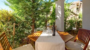 An outdoor patio with a wooden table and chairs, a bottle of wine, and a glass. - Cosy apartment for 4 people with pool, WIFI, A/C, TV, terrace and pets allowed (Senj)