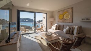 A modern living room with a large window, a sofa, a coffee table, and wicker chairs. - Modern townhouse with fantastic views of the Port of Sóller. (Port de Sóller)