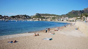 A beach with people sunbathing and swimming, a marina with boats, and buildings in the background. - Modern townhouse with fantastic views of the Port of Sóller. (Port de Sóller)
