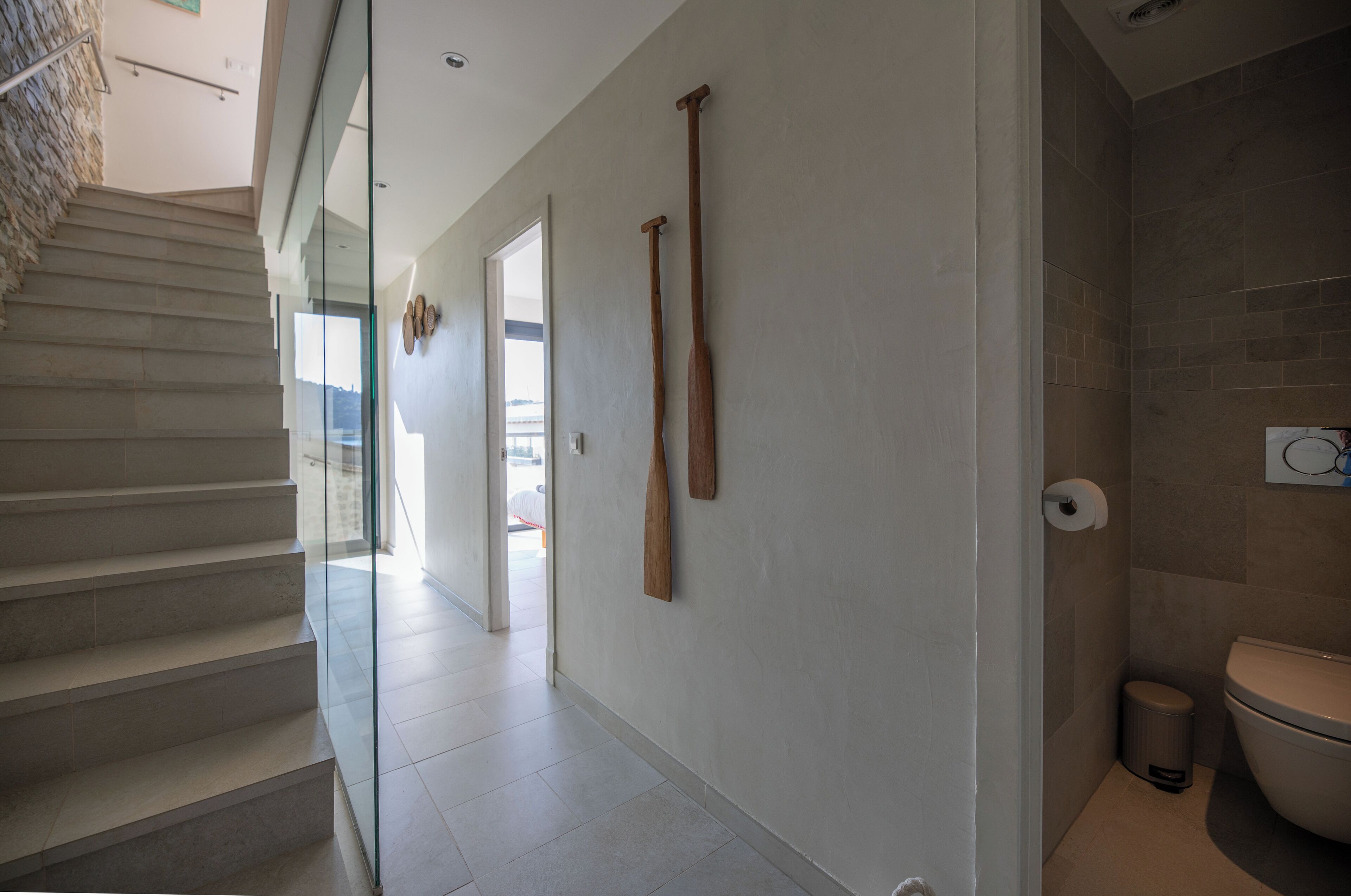 A modern interior with a staircase, a hallway, and a bathroom.