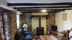 Una sala de estar acogedora con una pared de piedra, una chimenea, un sofá de cuero, una mesa de madera y un televisor.
