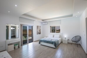 Une chambre à coucher avec un lit, un bureau, une chaise et une vue sur l’extérieur, visible à travers une porte vitrée.