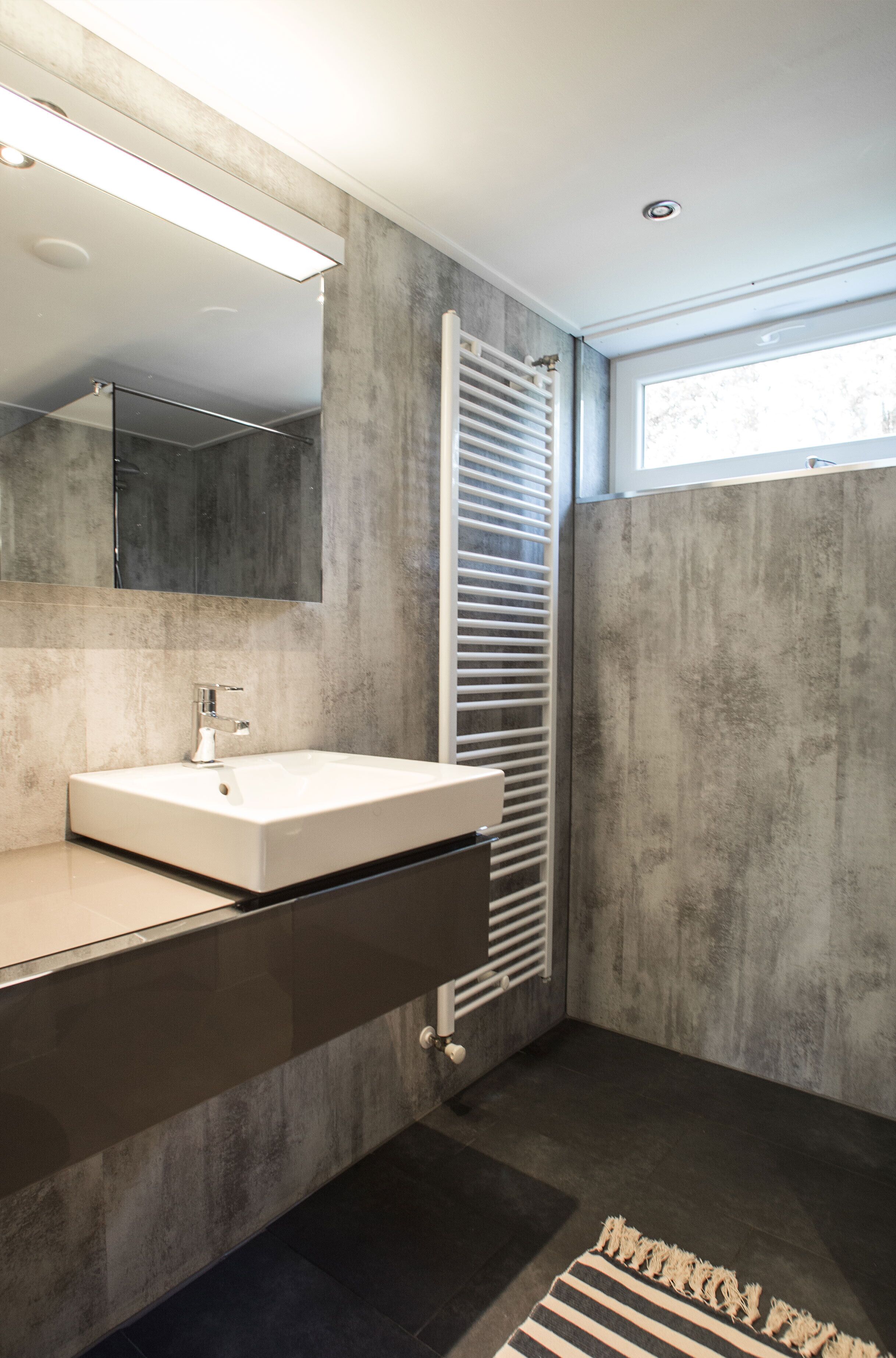 A modern bathroom with a large mirror, a white sink, and a towel rack.