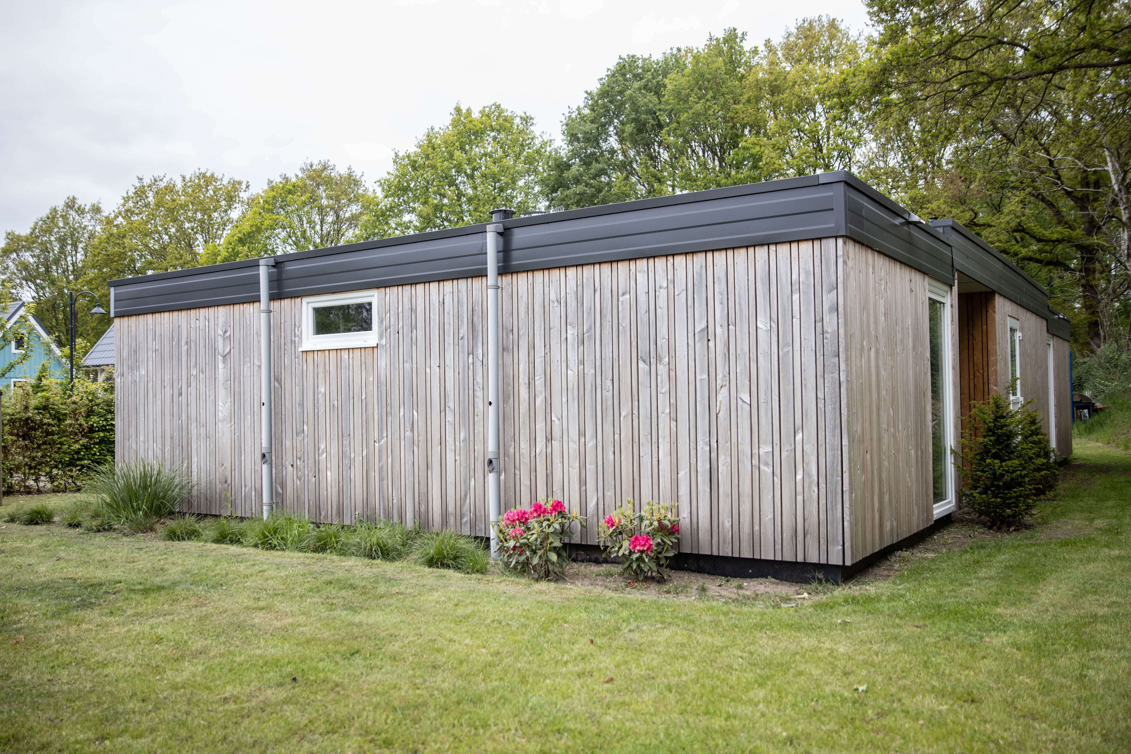 A wooden cabin with a black roof, a small window, and a door.