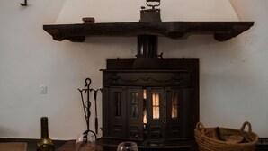 Een gezellige kamer met een open haard, een tafel met een fles en glazen, en wandlampen.