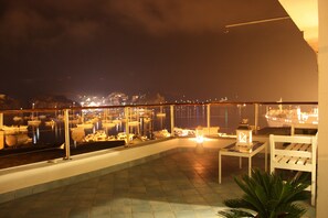A balcony with a view of boats, a table with a lantern, and a chair. - Attic on the harbor, Corso Carlo Pisacane 99, Ponza (Ponza)