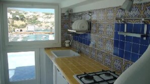 Una cocina con ventana, estufa y azulejos con diseño azulado.