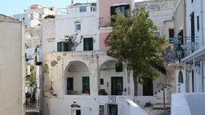 Una calle estrecha con edificios blancos, algunos con balcones y arcos.