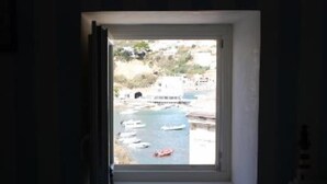 Una ventana con vistas al puerto, barcos y edificios.
