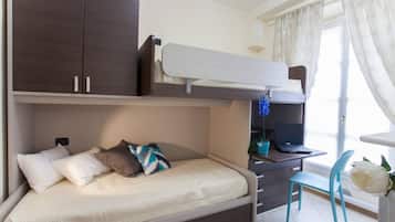 Ein Stockbett mit Schreibtisch und Stuhl, ein Laptop und ein Blumentopf.