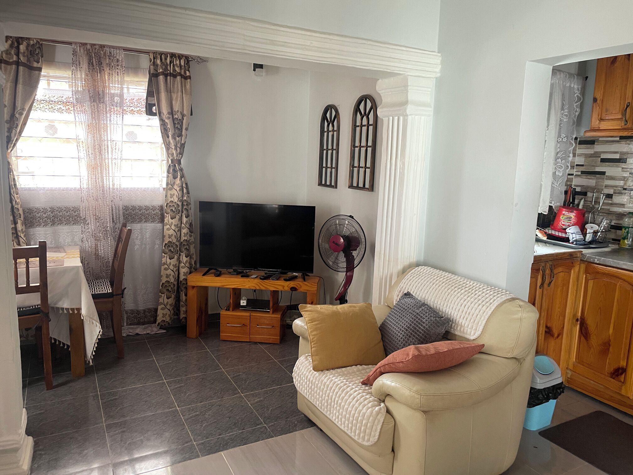 A living room with a TV, wooden furniture, a sofa, and a dining area with a table and chairs.