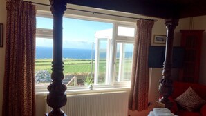 Una habitación con un ventanal grande, una cama con toallas ordenadas y vista al mar.