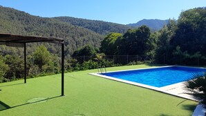 Une piscine offrant une vue dégagée sur le paysage environnant, notamment sur une zone herbeuse et une structure en forme de pergola.