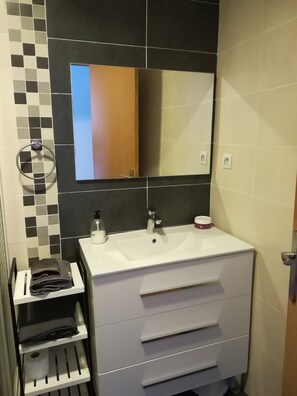 Une salle de bain moderne avec un lavabo blanc, un miroir et un porte-serviettes.