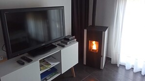 Un salon avec un téléviseur à écran plat posé sur un meuble blanc, une cheminée et une fenêtre avec des rideaux.