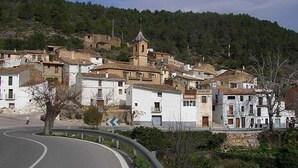 Un village perché sur une colline, avec ses bâtiments traditionnels en pierre, une église dotée d’un clocher et une route sinueuse.