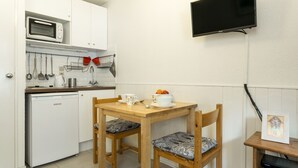 Une cuisine compacte équipée d’un four à micro-ondes, d’un petit réfrigérateur et d’une table à manger avec des chaises.