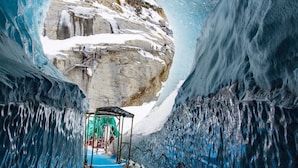 Un tunnel de glace offrant une vue dégagée sur une formation rocheuse enneigée au fond.