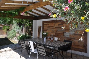 An outdoor patio with a table and chairs, a wooden pergola, and a stone wall. - Provencal villa with heated pool in beautiful surrondings, close to the beaches (Roquebrune-sur-Argens)