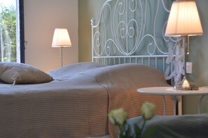 A bedroom with a bed, two bedside lamps, a small table, and a decorative metal headboard. - Provencal villa with heated pool in beautiful surrondings, close to the beaches (Roquebrune-sur-Argens)