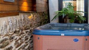 Ein Whirlpool mit Holzbank, einer Steinsäule und einem Schild, das die Nutzung des Whirlpools nach 22:00 Uhr untersagt.