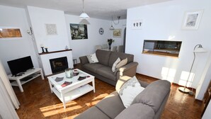 Una sala de estar con chimenea, televisión y sofá.