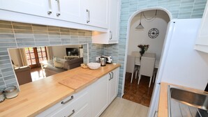 Una cocina moderna con armarios blancos, encimera de madera y pileta de acero inoxidable.