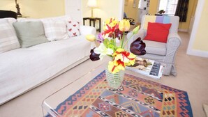 A living room with a sofa, a coffee table with a patterned rug, and a vase with flowers. - Elegant flat in Pimlico, close to Warwick Square (London)