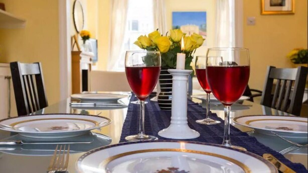 A dining table set with plates, cutlery, and glasses, with a vase of yellow flowers in the center. - Elegant flat in Pimlico, close to Warwick Square (London)