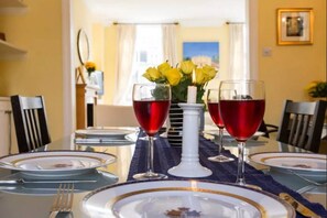 A dining table set with plates, cutlery, and glasses, with a vase of yellow flowers in the center. - Elegant flat in Pimlico, close to Warwick Square (London)