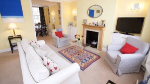 A living room with a sofa, armchairs, a TV, a fireplace, and a dining area. - Elegant flat in Pimlico, close to Warwick Square (London)