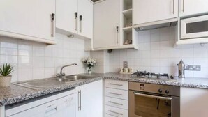 A modern kitchen with white cabinets, a granite countertop, a built-in dishwasher, and a stainless steel oven. - Elegant flat in Pimlico, close to Warwick Square (London)