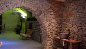 A stone-walled room with a fireplace, a wooden bench, and a chair. -  HIGH MONFERRATO STYLE HOUSE IN STONE AMONG THE VINEYARDS  (Acqui Terme)