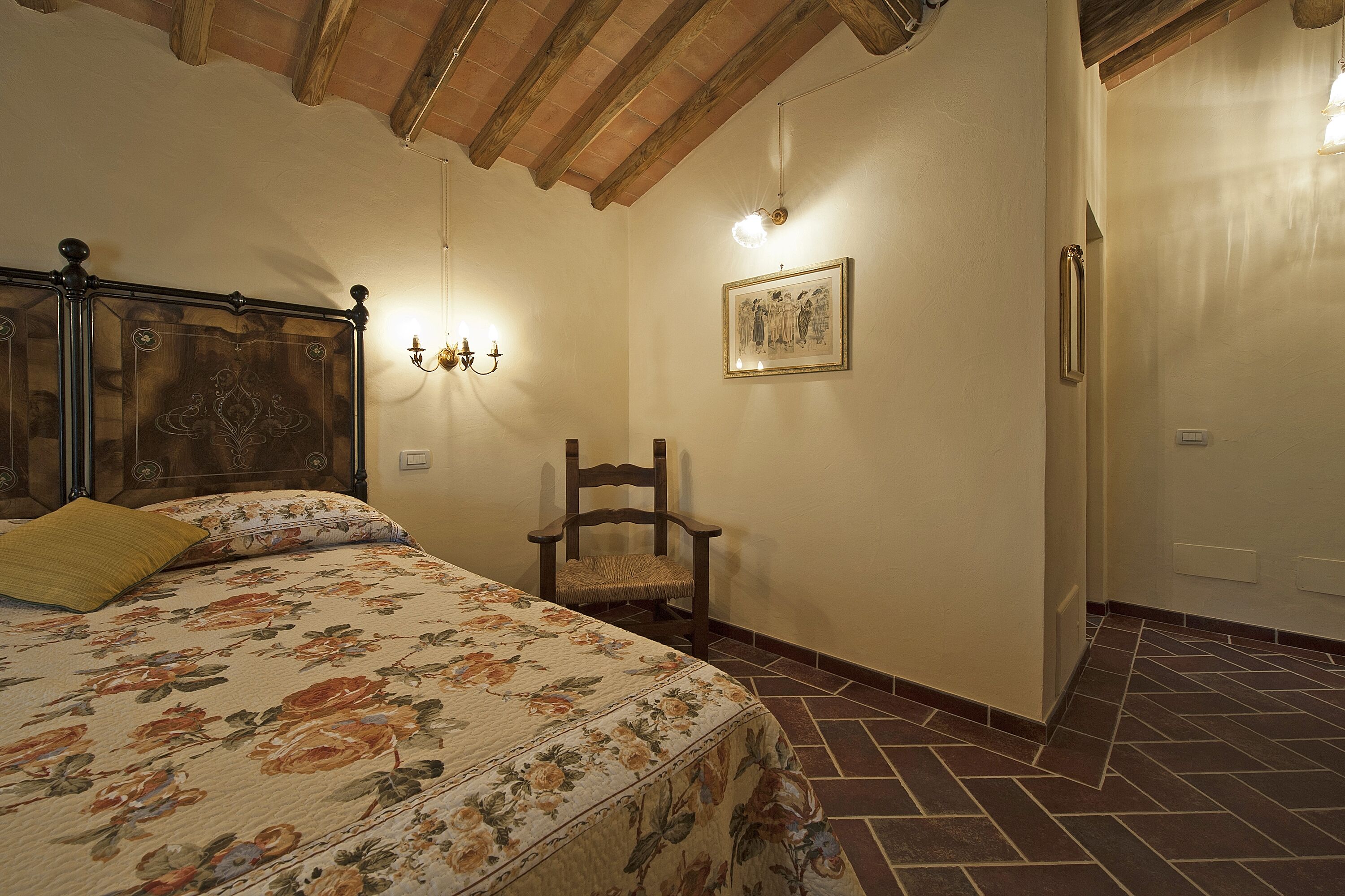 Une chambre à coucher avec un lit, une chaise, un tableau accroché au mur et un sol carrelé.