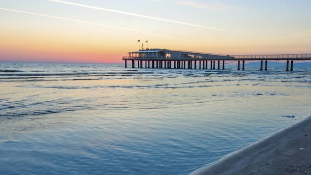 A pier extending into calm waters during sunset.