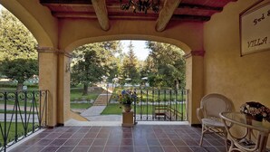 A covered patio area with a view of a park, a fountain, and a sign that reads "Bed & Villa".