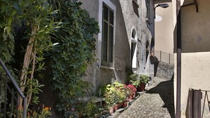 A narrow cobblestone street flanked by buildings with balconies, potted plants, and a small canal. - Lovely house close to the lake with panoramic lake and mountain views (Acquaseria, San Siro)