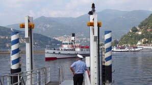 A pier with a man standing on it, a boat docked in the background, and a mountainous landscape in the distance. - Lovely house close to the lake with panoramic lake and mountain views (Acquaseria, San Siro)