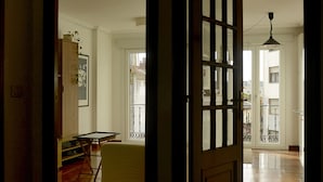 Une pièce spacieuse avec un plancher en bois, une grande fenêtre et une porte donnant sur une autre pièce.